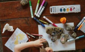 child's hand with art materials in table as featured image of article What is Play Therapy and Benefits of Play Therapy